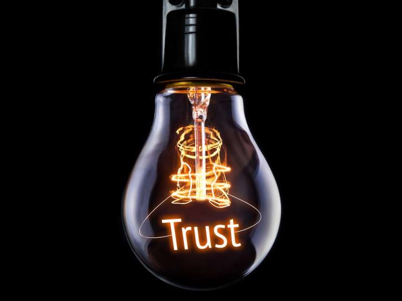 Lightbulb with the word 'trust' in gold lettering on a black background