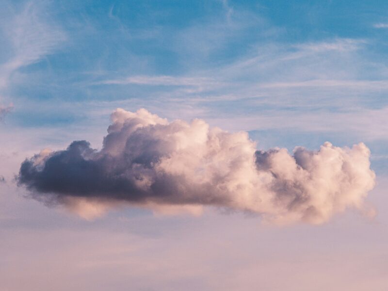 A purple sunset against a blue sky with a large cloud